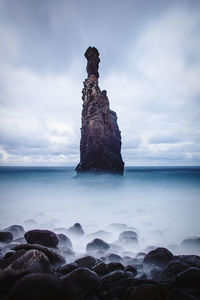 Rock formation on sea shore against sky