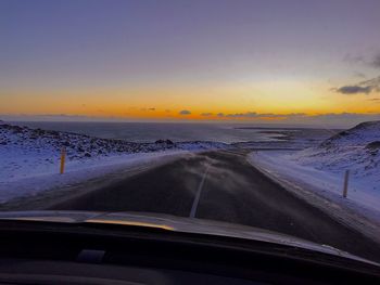 Road seen through car windshield during sunset