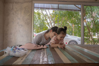 Rear view of woman sitting on window