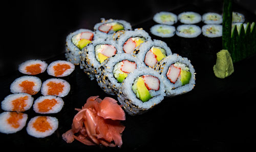 A close up shot of a selection of hosomaki and california sushi rolls served with ginger and wasabi