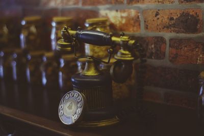 Close-up of old vintage telephone on table against brick wall