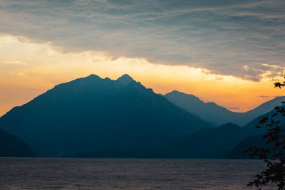 Scenic view of sea and silhouette mountains against sky during sunset