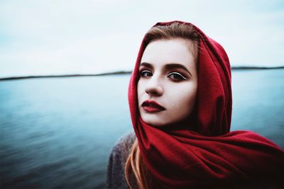 Close-up portrait of young woman standing against sea