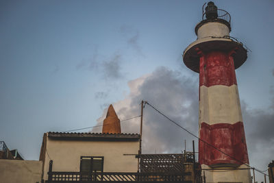 Low angle view of lighthouse against buildings and sky