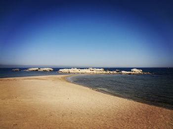 Scenic view of beach against clear blue sky