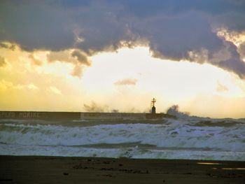 Scenic view of sea against cloudy sky during sunset