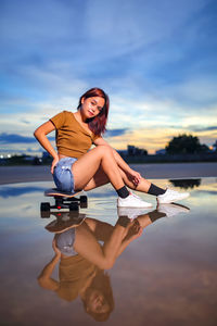 Young woman standing against sky during sunset