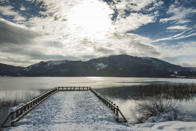 Scenic view of lake by snowcapped mountains against sky