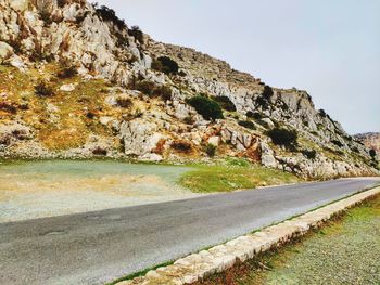 Road by rocks against sky