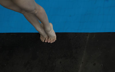 Low section of woman tiptoeing on poolside