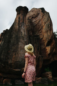 Rear view of mid adult woman standing against rock formation