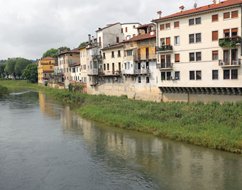 Buildings by river against sky