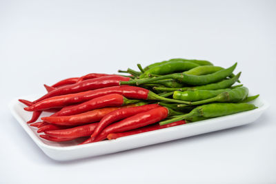 Close-up of red chili peppers over white background