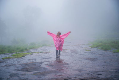 Rear view of woman standing on land during rainfall