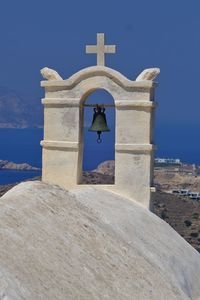 Low angle view of cross by building against blue sky