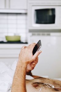 Midsection of man using smart phone at home