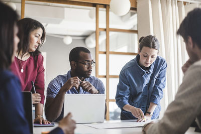 Businesswoman explaining strategy to colleagues on table in meeting at board room