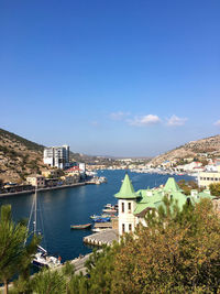 High angle view of city by sea against blue sky