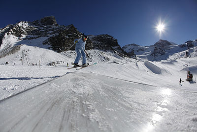 Person walking on snowcapped mountain against sky