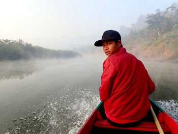 Rear view of young woman sitting on boat in lake