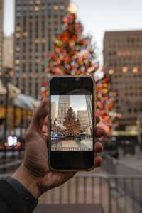 Cropped hands using mobile phone christmas tree