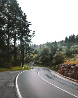 Road amidst trees against clear sky