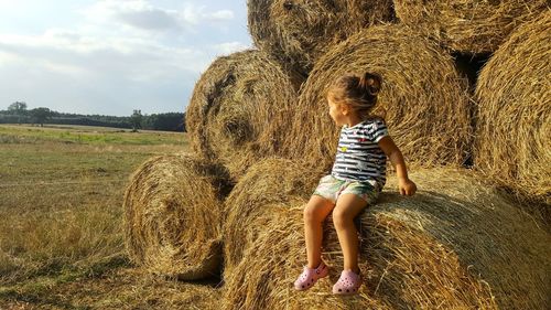 Smiling girl siting on hay bale