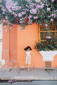 Full length of young woman standing on footpath in city