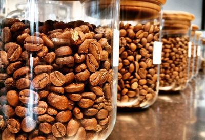 Close-up of roasted coffee beans in containers on table