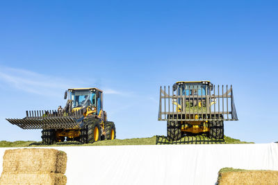 Tractors with front loaders against blue sky