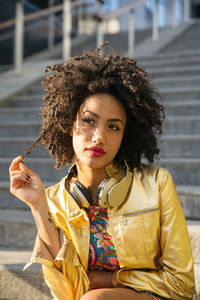 Fashionable young woman with curly hair in city