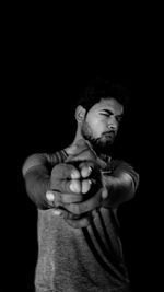 Portrait of young man against black background