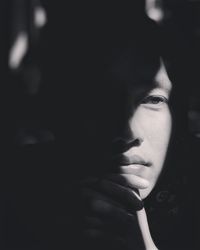 Close-up portrait of a young woman over black background