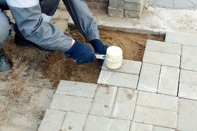 Bricklayer lays paving slabs outside. working man performs landscaping. builder lays out sidewalk