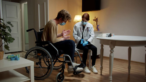 Young nurse checking temperature of patient at home