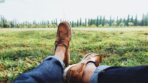 Low section of man sitting on grassy field