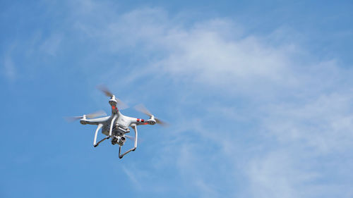 Low angle view of drone flying against sky