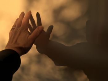 Close-up of man hand against sky during sunset