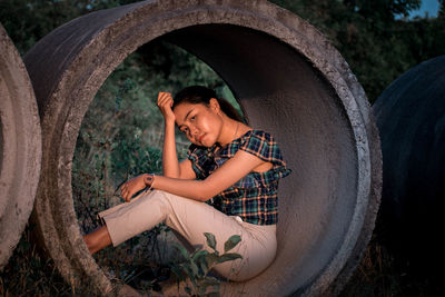Young man sitting in concrete pipe