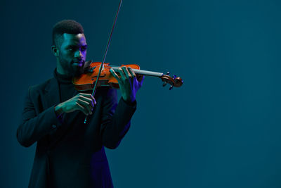 Midsection of man playing violin against clear sky