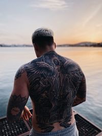 Side view of man looking at sea against sky during sunset