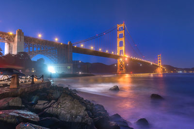 View of suspension bridge over river at night