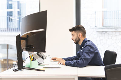 Young businessman working on laptop at desk in office