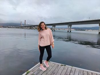 Full length portrait of woman standing on pier against sky