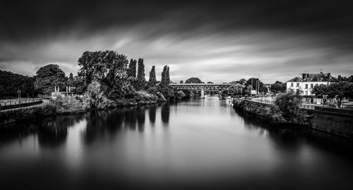 Bridge over river in city against sky