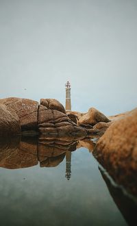 Reflection of hand on water against clear sky