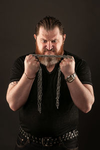 Portrait of mature man standing against black background