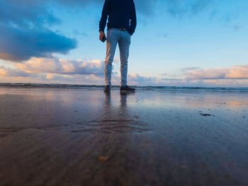 Low section of man standing at beach