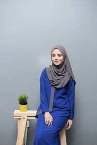 Portrait of young woman standing against white background