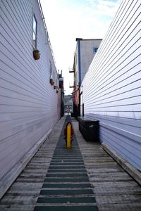 Young woman crouching behind bollard at alley
